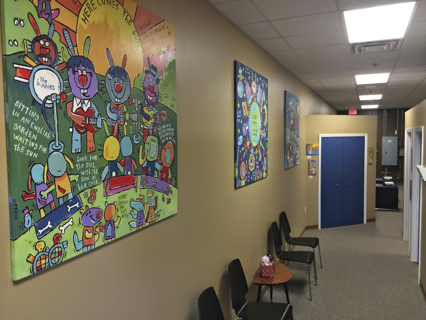 Waiting area View of the waiting area at Lake Nona Medical Injury Center: Joint Maneuvers Chiropractic Center. Chairs are lined up against a long hallway wall with several colorful modern artworks hanging on the wall.