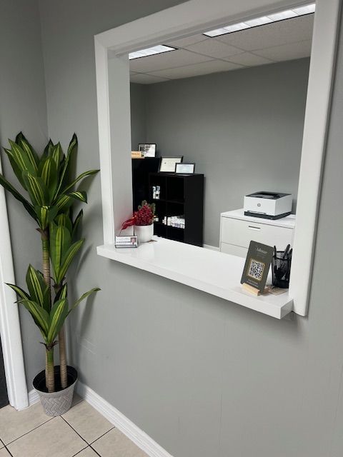 Reception Area View of reception desk which is a square opening through wall with counter in foreground an office on opposite side.